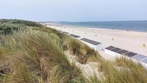 A beach with white buildings and yellow markers, surrounded by grass.