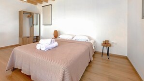 A neatly arranged bedroom with a bed, a bedside table, a mirror, and a wall-mounted light fixture.