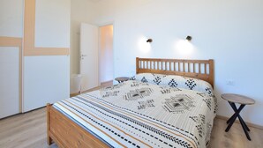 Una camera da letto con un letto in legno, biancheria a motivi decorativi, un piccolo tavolino e un lampadario a parete.