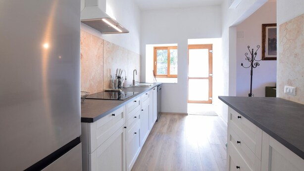 Una cucina moderna con mobili bianchi, un lavello in acciaio inossidabile e una finestra che offre luce naturale.