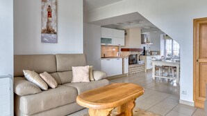 A modern living room with a sofa, a wooden coffee table, and a painting on the wall. - 2 bedroom amazing home in Créances (Créances)
