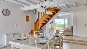 A dining area with a table set for four, a wooden staircase, and a view of the outdoors. - 2 bedroom amazing home in Créances (Créances)