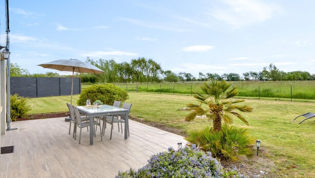 An outdoor patio with a table and chairs, a lamp, and a large umbrella. - 2 bedroom amazing home in Créances (Créances)