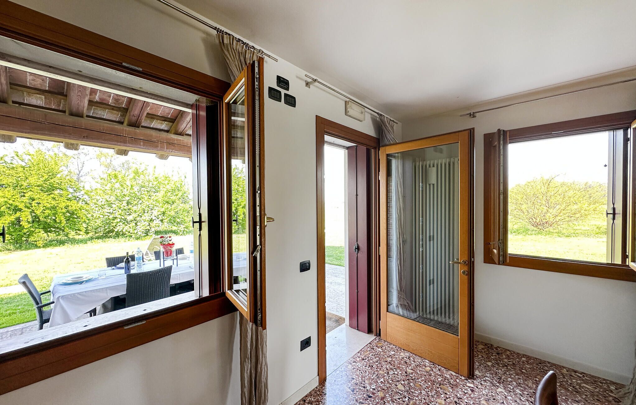 Habitació amb vista a un jardí, una porta que dona a l'exterior i una finestra amb vista a arbres.