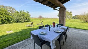 An outdoor dining area with a table set for four, surrounded by chairs, under a wooden pergola. - Cozy home in Rosà with WiFi (Rosà)
