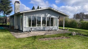 A single-story house with a large windowed porch, a chimney, and a small garden area. - Lovely home in Kirke Hyllinge (Kirke Hyllinge)