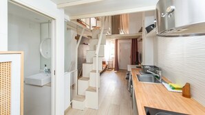A compact kitchen with a wooden countertop and stainless steel appliances, a white sink, and a staircase leading to an upper level. - GuestReady - Confy Flat in Madrid (Madrid)