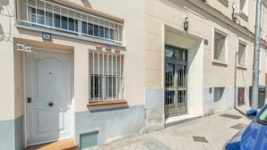 A building with a white door, a window with metal bars, and a blue car parked outside. - GuestReady - Confy Flat in Madrid (Madrid)