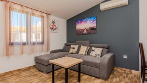 A living room with a grey sofa, a wooden coffee table, and a painting of a beach scene. - Beautiful apartment in Vir with WiFi (Vir)