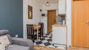 A compact living space with a kitchenette, a dining area with a table and chairs, and a grey sofa. - Beautiful apartment in Vir with WiFi (Vir)
