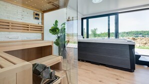 Ein moderner Spa-Bereich mit Holzbänken, einer Glastrennwand und einem großen Fenster mit Blick auf die Landschaft.