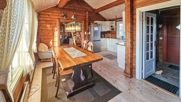 A cozy log cabin interior with a dining area, kitchen, and a door leading outside. - Stunning home in Flesberg with sauna (Flesberg)