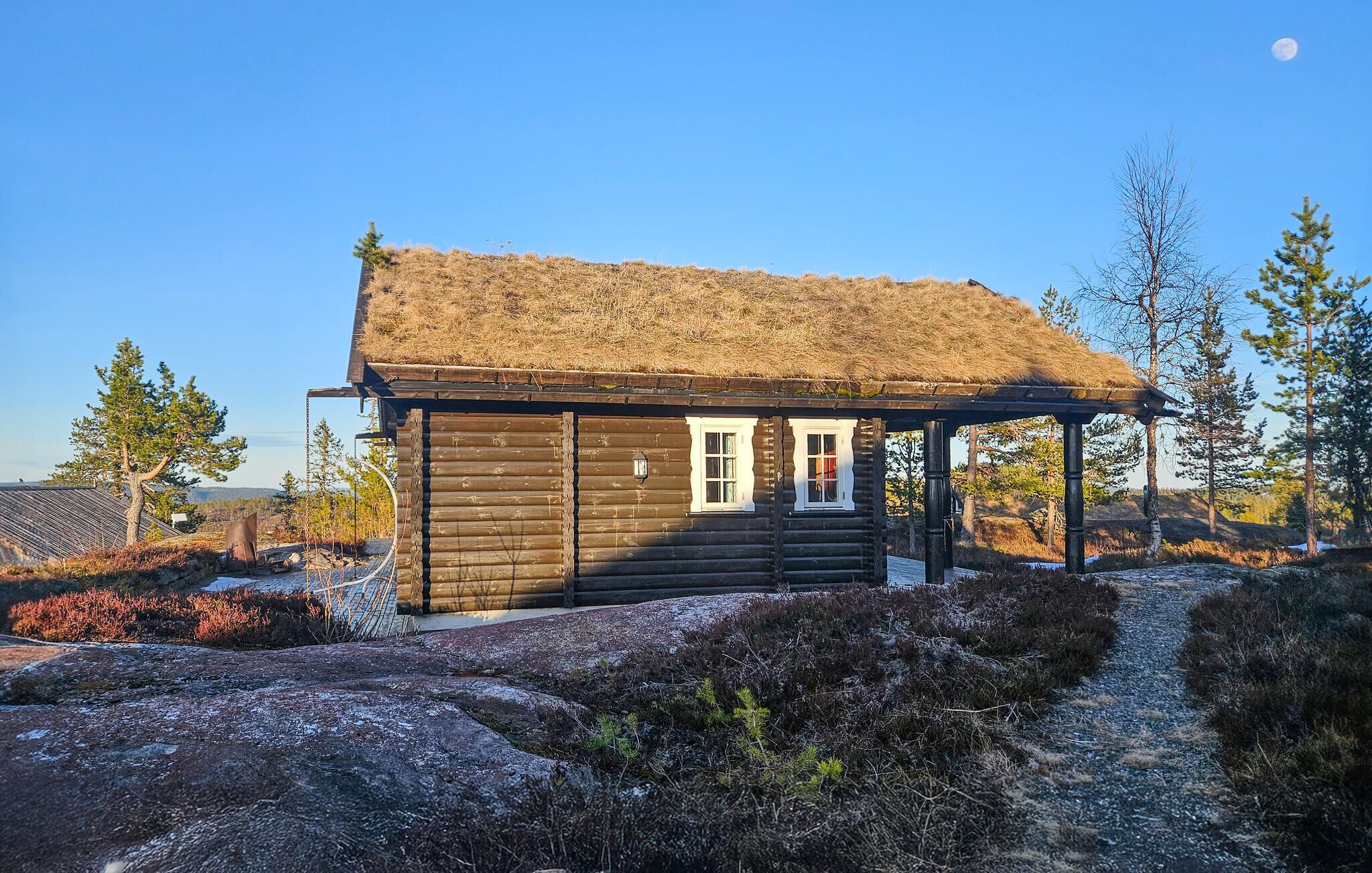 A log cabin with a thatched roof, a porch, and a small door.