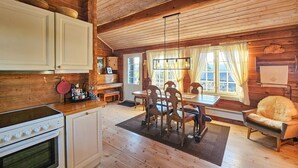A cozy cabin-style kitchen with a dining area, wooden floors, and a large window with curtains. - Stunning home in Flesberg with sauna (Flesberg)