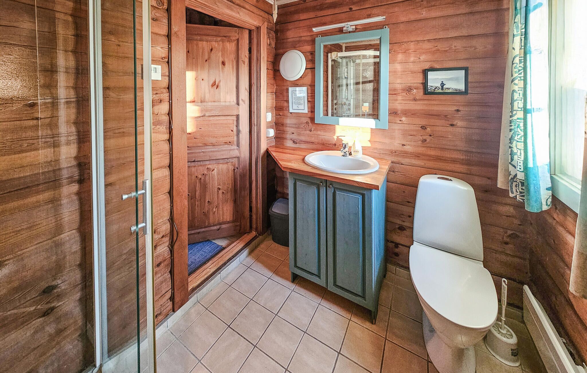 Ein Badezimmer einer Holzhütte mit Waschbecken, Spiegel und Toilette.