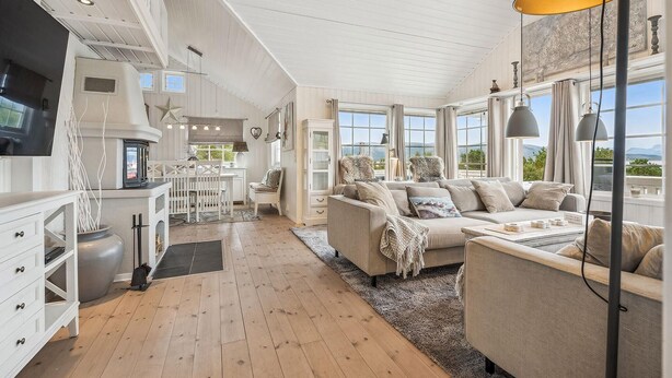 A spacious living area with a sofa, a dining table, and a kitchen in the background. - 4 bedroom beautiful home in Lødingen (Lødingen)