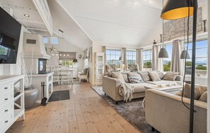 A spacious living area with a sofa, a dining table, and a kitchen in the background. - 4 bedroom beautiful home in Lødingen (Lødingen)