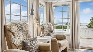 A cozy seating area with a view of a lake and mountains, featuring plush chairs and a table with a lamp. - 4 bedroom beautiful home in Lødingen (Lødingen)