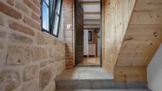 A narrow staircase leading to a wooden loft bedroom with a brick wall and a window. - Awesome home in Pirovac with WiFi (Pirovac)