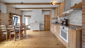 A kitchen with wooden beams, a dining area with a table and chairs, and a brick wall. - Awesome home in Pirovac with WiFi (Pirovac)