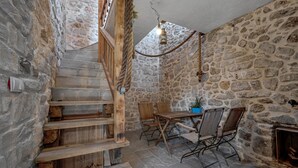 A rustic stone interior with a wooden staircase, a dining table with chairs, and a hanging light fixture. - Awesome home in Pirovac with WiFi (Pirovac)