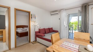 Una habitación moderna y luminosa con cama, sofá, mesa de comedor y aire acondicionado.