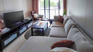 A modern living room with a flat-screen TV, a sofa, a coffee table, and a chair.