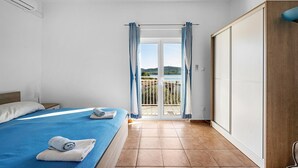 A bedroom with a bed, a wardrobe, and a view of a balcony with a scenic landscape. - Stunning apartment in Pirovac with WiFi (Pirovac)