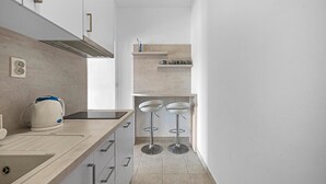 A narrow kitchen with a built-in stove, a kettle, and two bar stools. - Stunning apartment in Pirovac with WiFi (Pirovac)