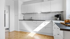 A modern kitchen with white cabinets, a black countertop, and a wooden floor. - 2 bedroom amazing home in Ringkøbing (Ringkøbing)