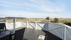 A rooftop terrace with a view of a rural landscape, featuring a table with chairs and a bottle. - 2 bedroom amazing home in Ringkøbing (Ringkøbing)