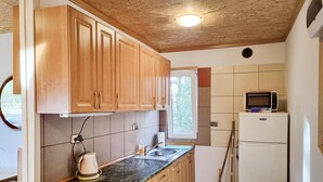 A compact kitchen with wooden cabinets, a microwave, a refrigerator, and a window providing natural light. - Cozy home in Plock with house a panoramic view (Plock)