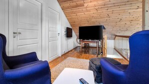 Una sala de estar con techo de madera, televisor de pantalla plana y sillas azules.