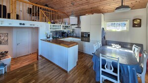 Una cocina amplia con techo de madera, una isla central y una zona de comedor con mesa y sillas.