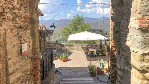 A stone staircase leading to a terrace with a white umbrella, potted plants, and a view of distant mountains. - Nice home in Monte S.Maria Tiberina (Monte S.Maria Tiberina)
