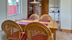 A dining area with a wooden table, wicker chairs, and a kitchen in the background.