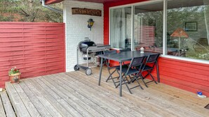A covered outdoor patio with a grill, a table, and chairs.