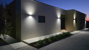 A modern building with a flat roof, rectangular windows, and a well-lit entrance. - Lovely home in Galizana (Galizana)