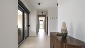 A modern hallway with a wooden console table, a glass door, and a view into an adjacent room. - Lovely home in Galizana (Galizana)