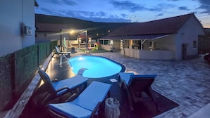 A swimming pool with lounge chairs and a slide, surrounded by buildings and a hilly landscape. - Gorgeous home in Kricke (Kricke)
