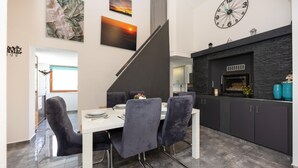 A modern kitchen with a stone backsplash, a built-in oven, and a dining area with a white table and four chairs. - Gorgeous home in Kricke (Kricke)