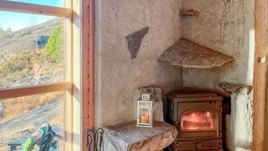A rustic interior with a stone fireplace, a small lantern, and a view of a mountainous landscape through a window. - Beautiful home in Masfjordnes with sauna (Masfjordnes)