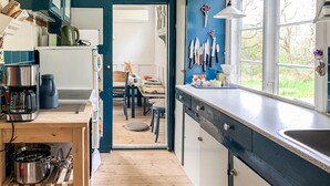 A kitchen with a wooden floor, a coffee machine, a kettle, and a sink. There is a window with a view of greenery outside. - Cozy home in Knebel with WiFi (Knebel)