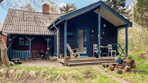 A rustic cabin with a porch, a small shed, and a garden area with potted plants. - Cozy home in Knebel with WiFi (Knebel)