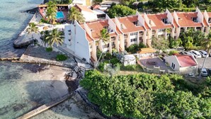 Ilmakuva rannikolla sijaitsevasta hotellista, jossa on useita rakennuksia, uima-allas ja ranta.