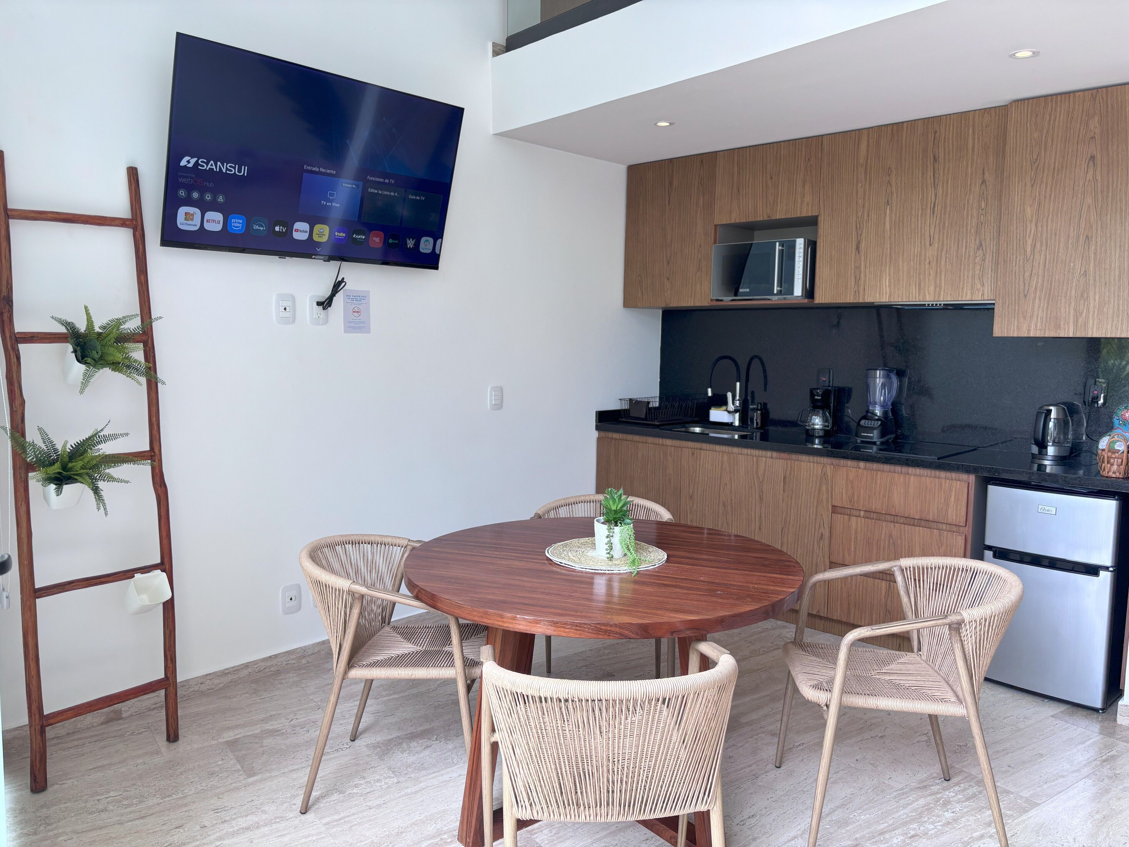 Een moderne keuken met houten kastjes, een roestvrijstalen koelkast en een flatscreen televisie aan de muur.