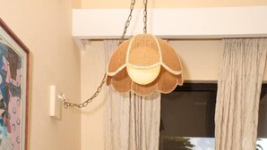 Un tavolo da pranzo con un sottopiattino intrecciato, tovaglioli verdi e un lampadario.