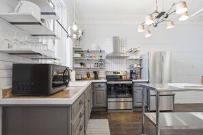 A modern kitchen with stainless steel appliances, white cabinetry, and pendant lighting. - Cozy 2BR Loft in Downtown Charleston, IL (Charleston)