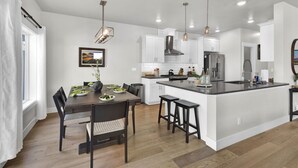 A modern kitchen with white cabinets, a central island, and pendant lighting. - Hillside Harmony Luxury Comfort (Boise)