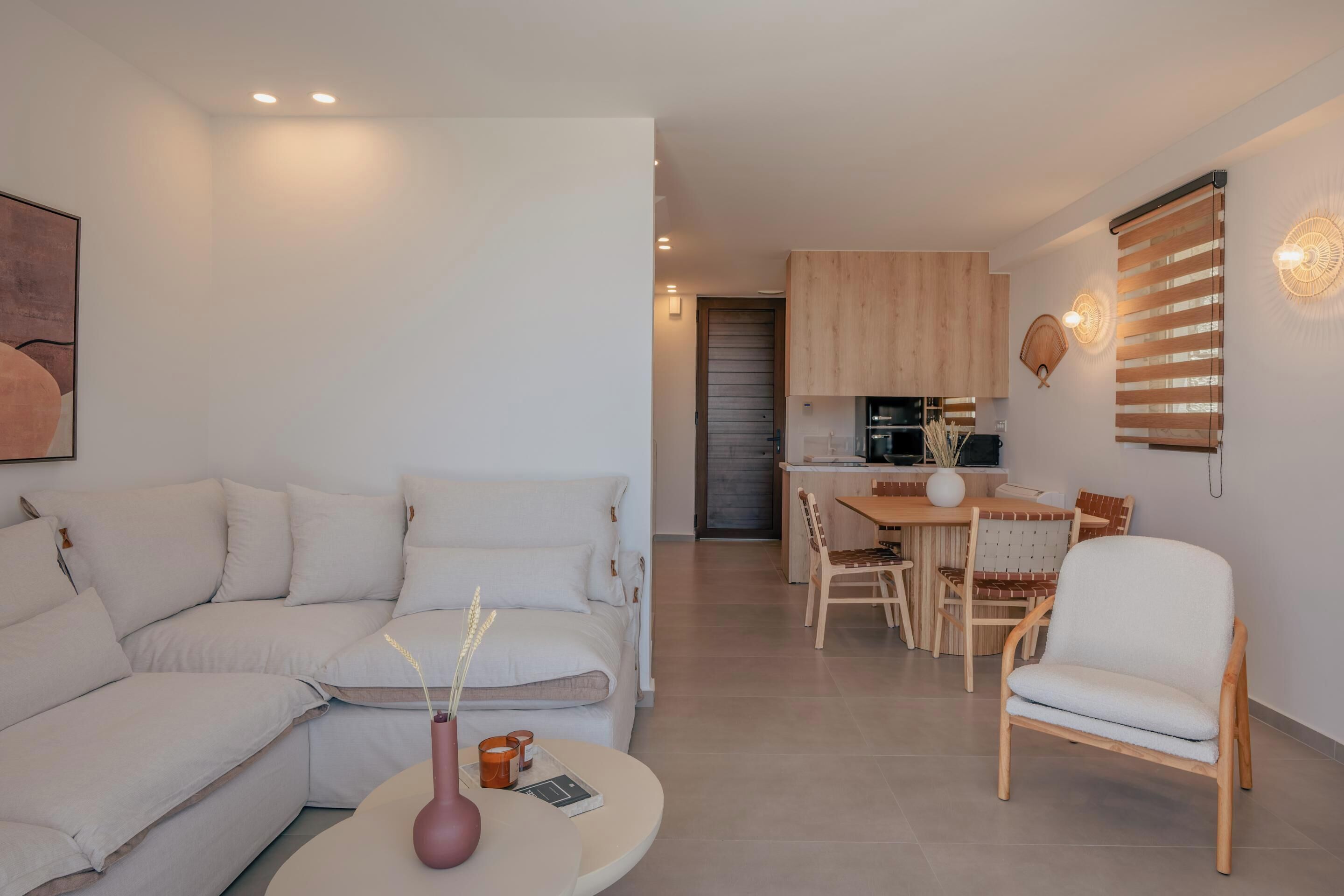 A modern living room with a sofa, a coffee table, and a dining area with wooden furniture.